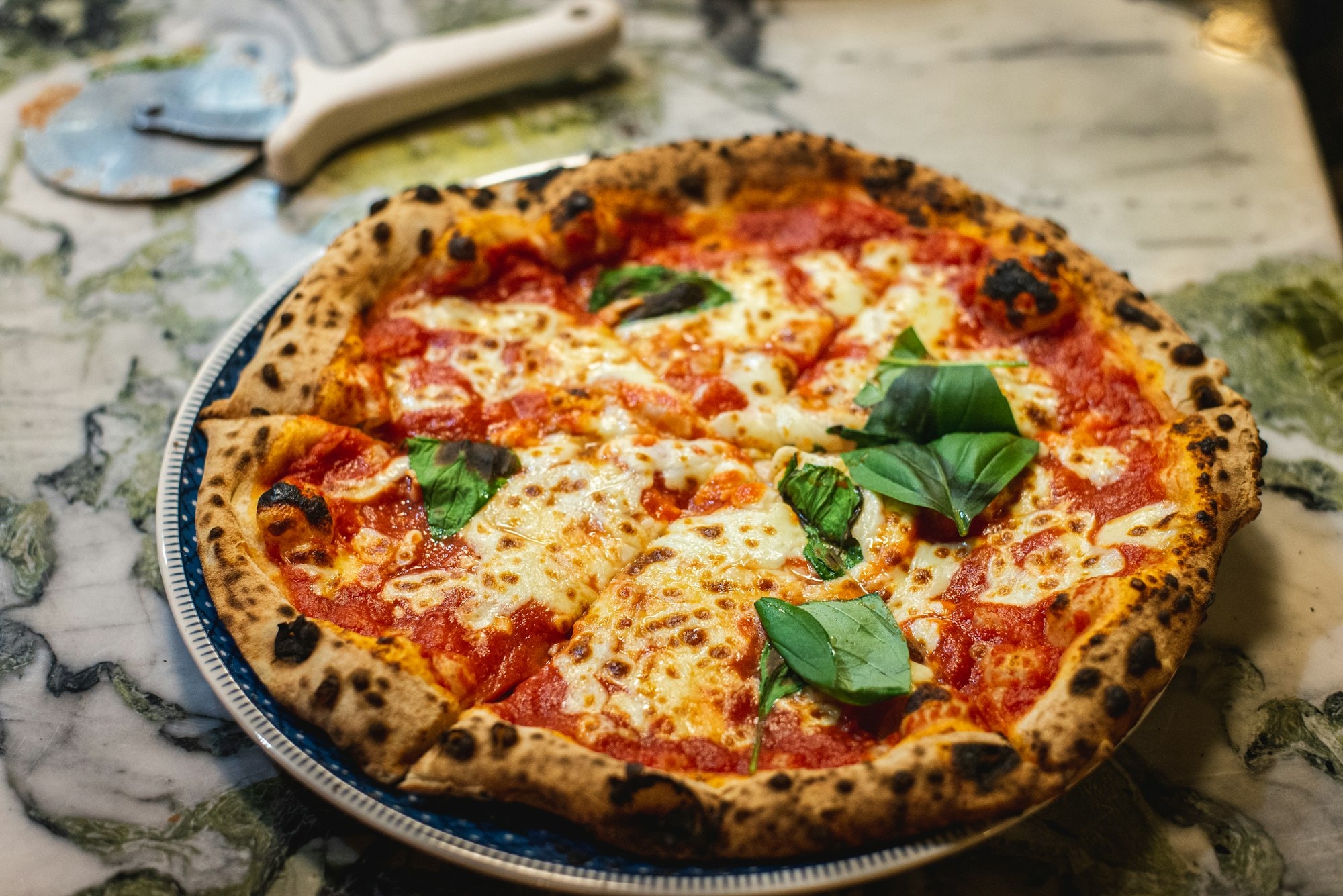 Wood-fired pizza on a peel inside a restaurant kitchen
